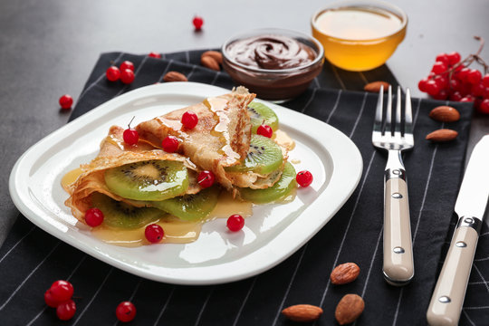 Delicious pancakes with kiwi and viburnum on white plate