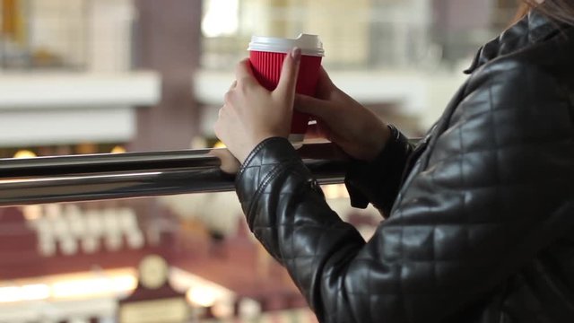 Her hands holding a red cup of coffee. Coffee to go