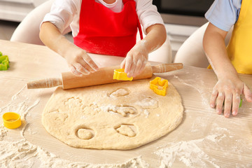 Little children making Easter cookies at kitchen, closeup