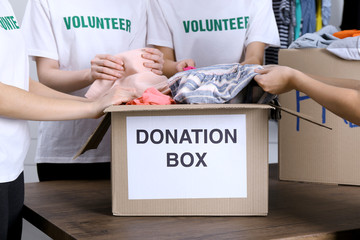 Female volunteers preparing donation box with clothes