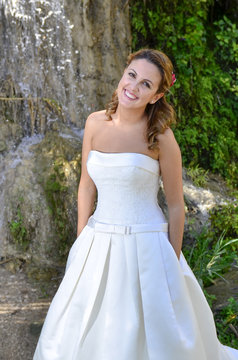Guapa novia reci&eacute;n casada junto a una cascada.