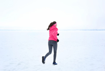 Back view of young woman jogging on winter day