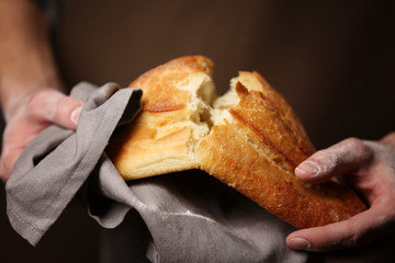 Male hands breaking freshly baked bread, closeup