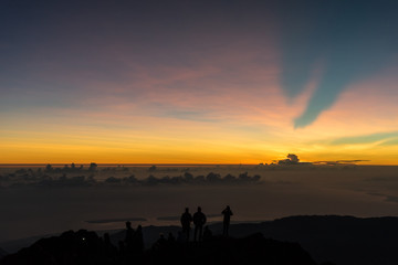 People watching Sunrise on Mount Rinjani Summit. Hikers watching the sunrise on 3726m Gunung RInjani Summit after demanding hike in the dark. Lombok Indonesia.