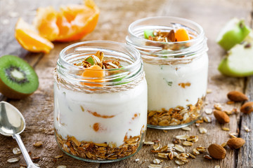 Granola with yogurt and fruits in a rustic jar. Delicious healthy American food for breakfast. Traditional US snack. Close-up shot.