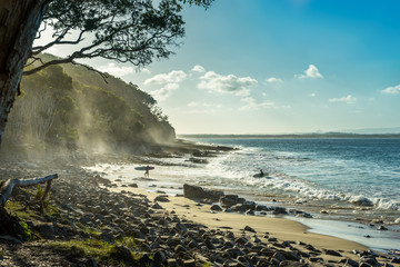 Tropical Surfer Beach. Idyllic sunset at famous Tea Tree Bay, Noosa, Australia. Sun shining through...