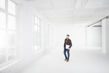 Wide shot of the white office interior with businessman walking with laptop