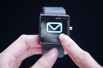 Hand touching message icon on smartwatch.