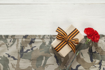 Gift box with red carnation and st george ribbons on the khaki b
