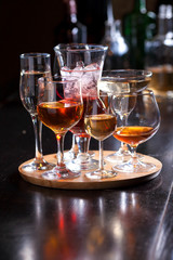 glasses of different shapes with different alcohol on a wooden round board on the bar