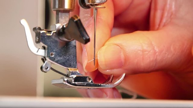 Tailor Preparing Sewing Machine.
Tailor threading the sewing machine needle.
Caucasian mature woman doing dressmaking.
