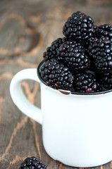 Fresh blackberries in a big white cup wooden board