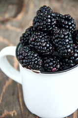 Fresh blackberries in a big white cup wooden board