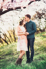 Young couple in love having a date under pink cherry blossom trees. Love and tenderness in spring season