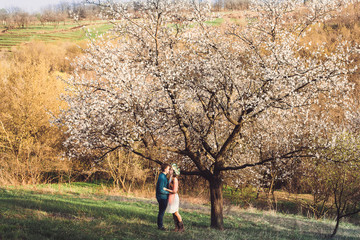 Love and tenderness. Beautiful young loving couple embracing in blossom spring garden. Romantic dating.