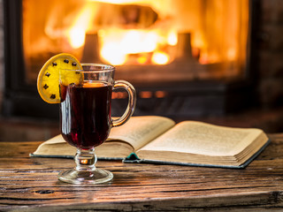 Hot mulled wine and a book on the wooden table.