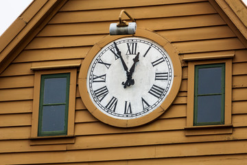 Fototapeta na wymiar Antique clock on the facade of a wooden building