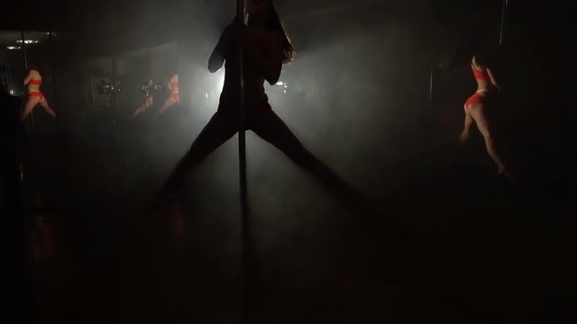 Young slim sexy pole dance woman exercising in studio.
