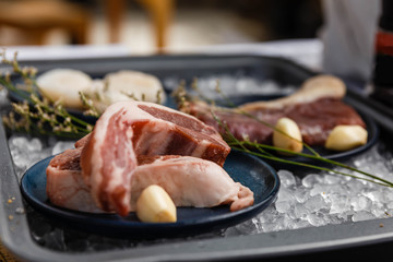 Beef, Pork, and Scallop Preparing for Cooking on Iced Plate with Olive Oil, Wine, Half of Onion and Black Pepper on Newspaper.
