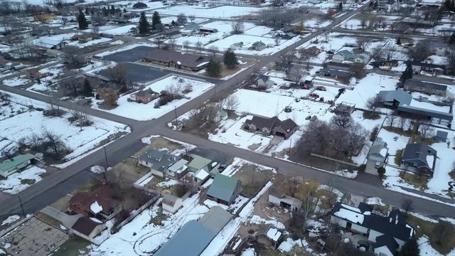 Aerial flight across rural town winter snow. Winter storm blizzard fresh white snow. Rural farm community. Hard seasonal weather. Hazard to driving. Surveillance spy.