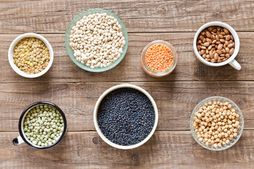 Verschiedene getrocknete Hülsenfrüchte in Schüsseln auf einem Holztisch