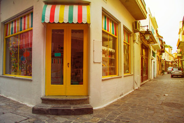 Fototapeta na wymiar Traditional multicolor facade of shop from the street greek island town panorama. Image with sunkissed effect, toned