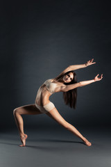 Fototapeta na wymiar Young slim contemporary dancer posing on a black studio background