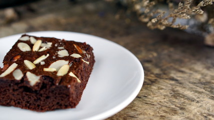 Fototapeta na wymiar Sweet chocolate brownies put on a wood table with dark roasting coffee beans.