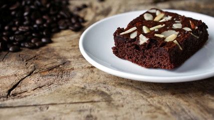 Sweet chocolate brownies put on a wood table with dark roasting coffee beans.