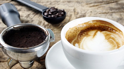 Cappuccino Coffee. A cup of latte, cappuccino or espresso coffee with milk put on a wood table with dark roasting coffee beans. Drawing the foam milk on top.