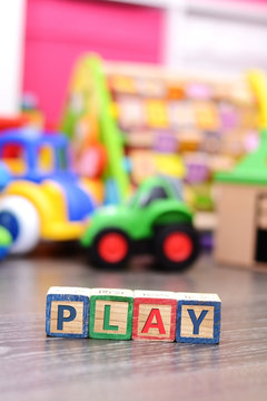 Play word from colorful cubes with many toys on background
