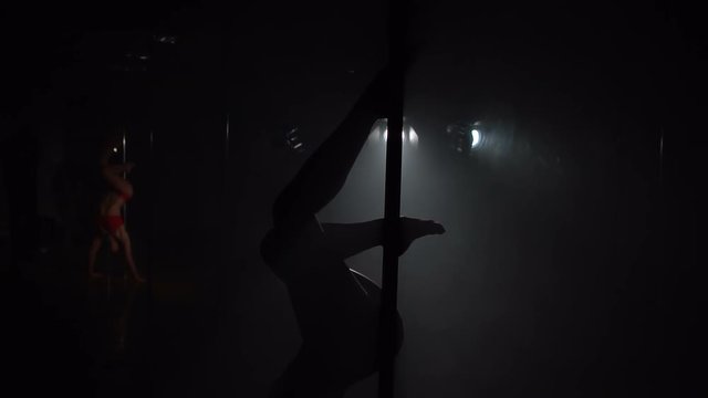 Flexible pole dancer posing upside down on pylon, slow motion.