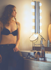 Young woman looking herself in the mirror on bathroom