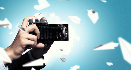 Businessman taking photo with vintage camera . Mixed media