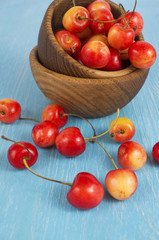 Background of ripe cherries. Pile of fresh and tasty cherries in wooden bowl. Fresh cherries scattered on a wooden table. 