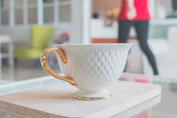 White cup of coffee on wooden table in the coffee shop.