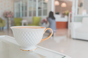 White cup of coffee on wooden table in the coffee shop.