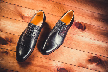 Black leather men's shoes on a wooden background