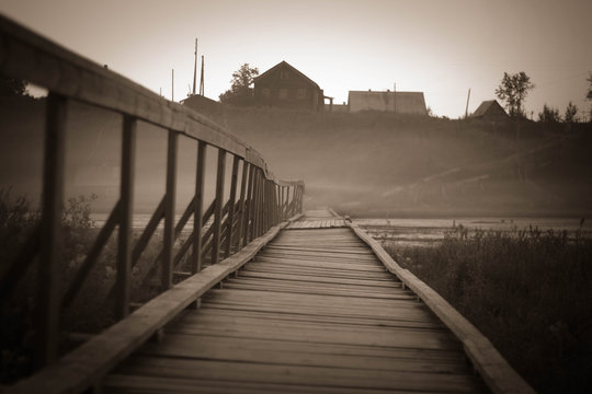 Old wooden bridge to village hill. Vintage gothic rustic black and white photo