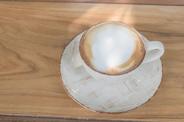 White cup of coffee on wooden table in the coffee shop.