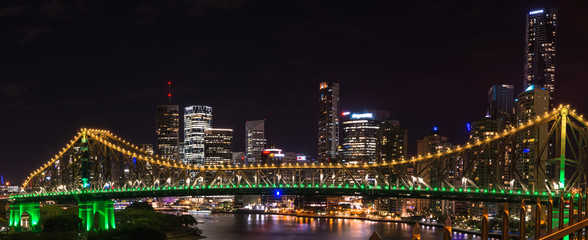 Panoramic view of Story bridge in yellow and green light at nigh time in Brisbane Australia  