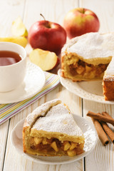Apple pie and cup of tea on white wooden background.