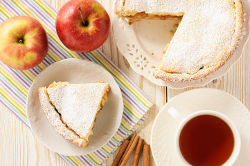 Apple pie and cup of tea on white wooden background.