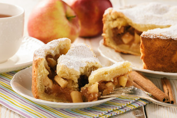 Apple pie and cup of tea on white wooden background.