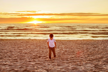 Fototapeta na wymiar boy goes on sand on the beach. sea at sunset