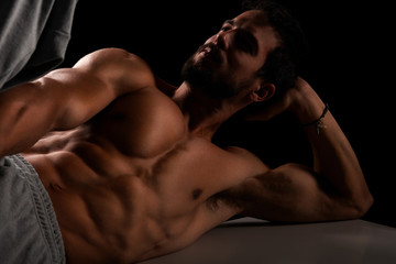 Fototapeta na wymiar Handsome muscular model lying on bench