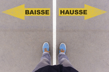 Baisse and Hausse text arrows on asphalt ground, feet and shoes