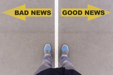 Bad news, good news text arrows on asphalt ground, feet and shoe