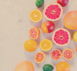 Mix of whole an cut citruses on white wooden table, top view, retro toned