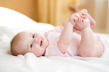 Funny chubby baby infant girl playing with her feet - 136941036
